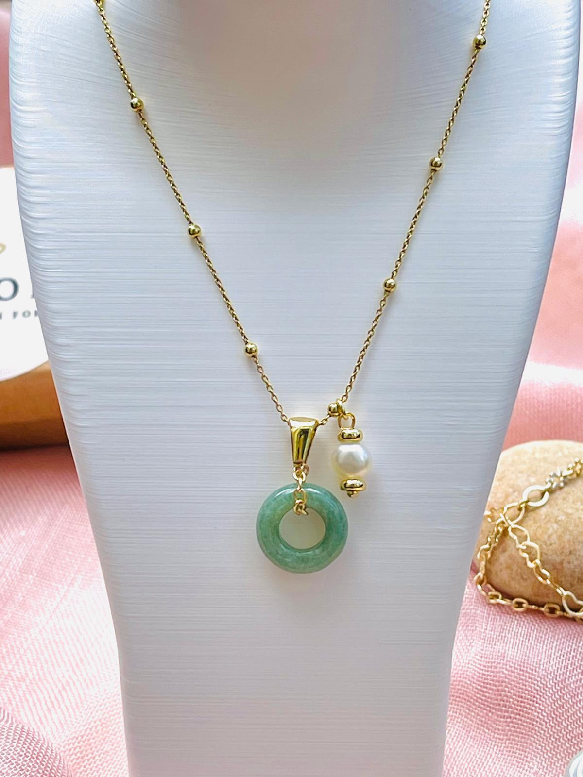 Close-up of natural jade pendant, pearl accent and gold plated details